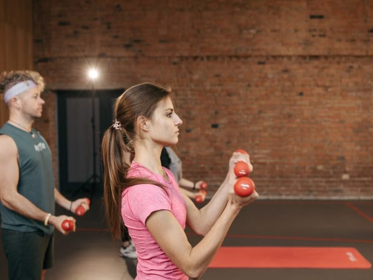 Group of adults exercising indoors with dumbbells, focused on fitness and health.