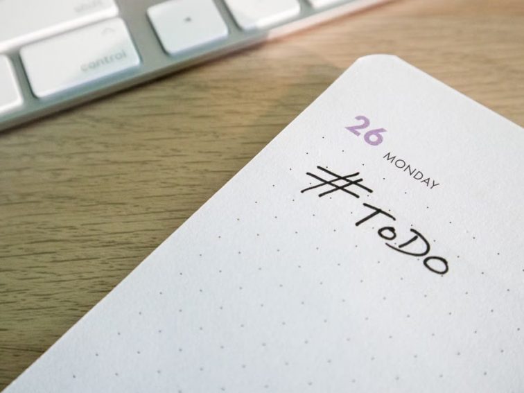 Close-up of a to-do list next to a computer keyboard on a desk.
